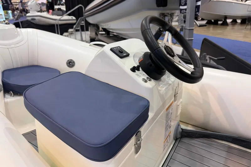 Slide: The Image of 2026 Brig Falcon 330 boat interior with steering wheel and blue cushioned seats. - 15