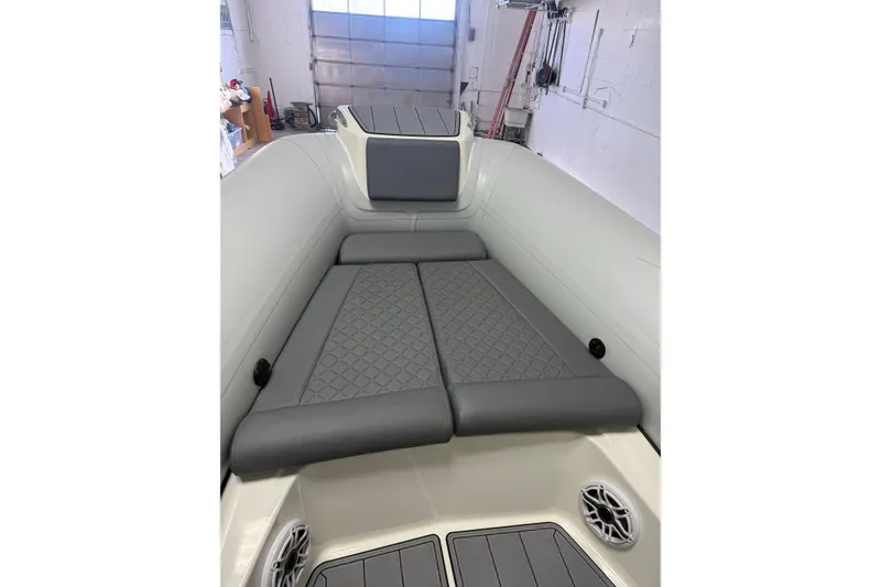Slide: The Image of 2026 Brig Eagle 8 boat interior with gray cushioned seating in a garage setting. - 22