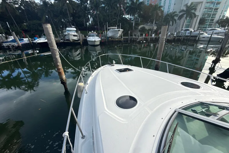 Slide: The Image of 2002 Sea Ray 320 Sundancer docked in a marina with surrounding boats and palm trees. - 14