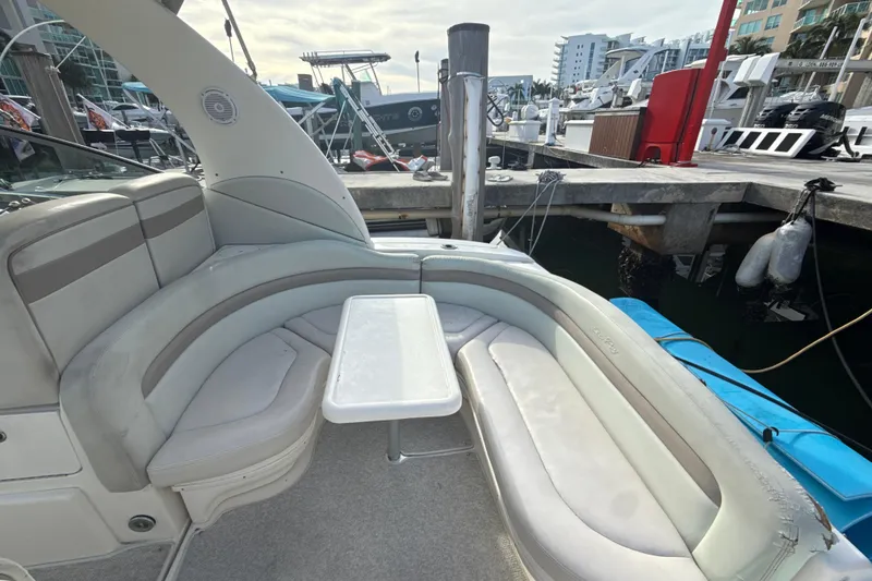 Slide: The Image of 2002 Sea Ray 320 Sundancer boat interior with curved seating and table at marina. - 5
