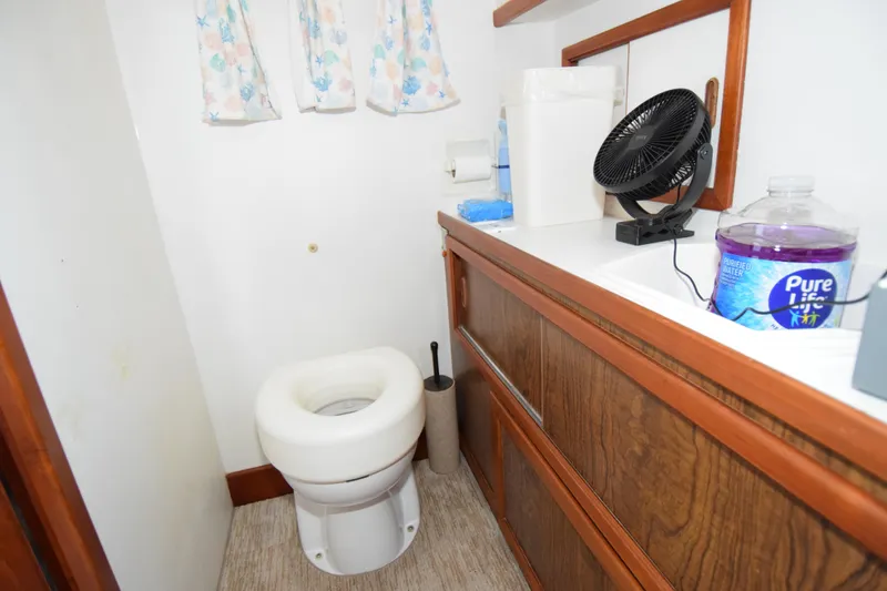 Slide: The Image of Small bathroom in a 1966 Drake 53 boat with wooden cabinets and portable fan. - 17