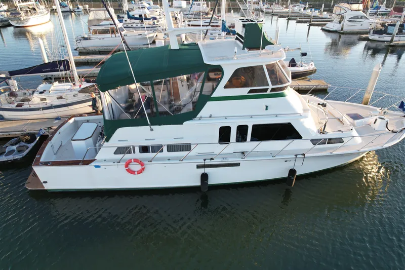 Slide: The Image of 1966 Drake 53 yacht with green canopy docked in marina, surrounded by other boats. - 2