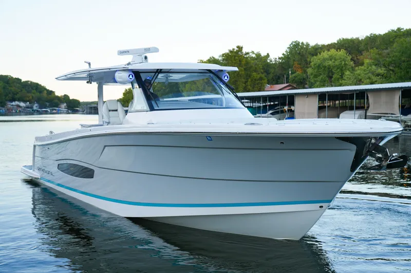 The Image of 2021 Regal 38 SAV boat on calm water near a marina. - 0