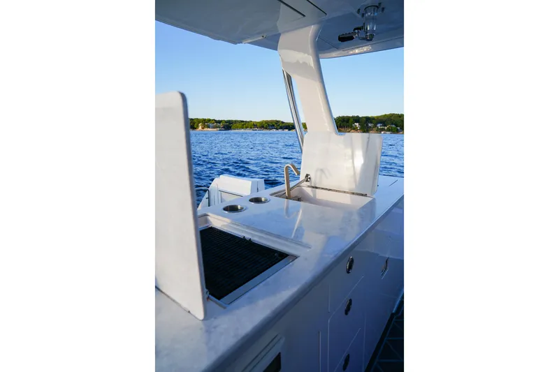 Slide: The Image of 2021 Regal 38 SAV boat kitchen area with sink, overlooking serene lake view. - 15