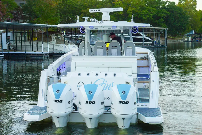 Slide: The Image of 2021 Regal 38 SAV boat with triple Yamaha 300 engines docked on a calm lake. - 6
