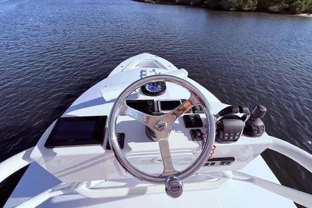 Slide: The Image of 2017 Regulator 41 boat helm with steering wheel and navigation equipment on calm water. - 64