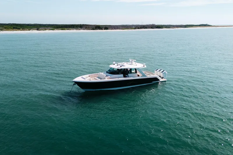 Slide: The Image of 2023 Tiara 48 yacht cruising on calm blue waters near a scenic coastline. - 3