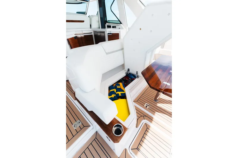Slide: The Image of 2023 Tiara 48 yacht interior with white seating, wooden table, and storage compartment. - 30