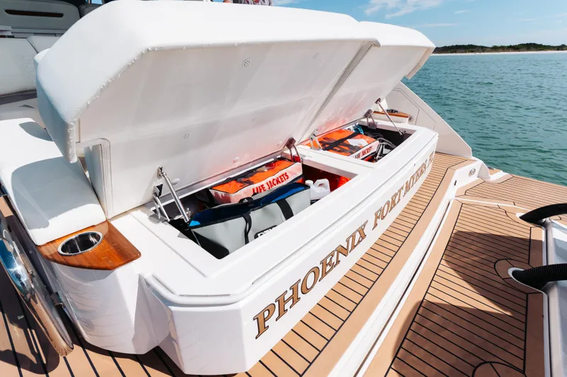 Slide: The Image of 2023 Tiara 48 yacht storage compartment with life jackets, docked on calm water. - 31