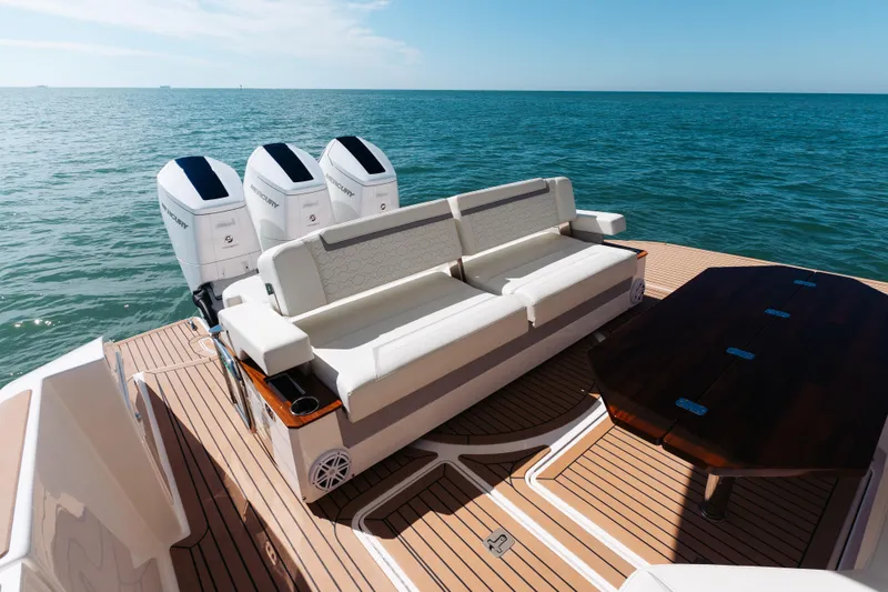 Slide: The Image of 2023 Tiara 48 yacht deck with seating, table, and triple outboard engines on open water. - 37