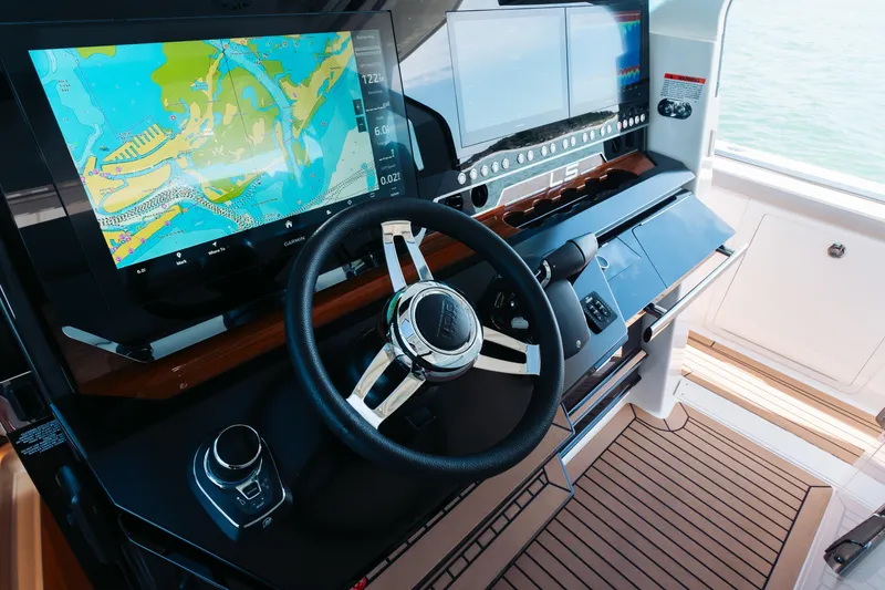 Slide: The Image of 2023 Tiara 48 yacht helm with advanced navigation screens and steering wheel. - 52