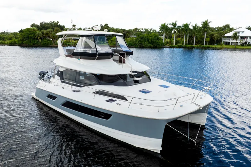 Slide: The Image of 2019 Aquila 44 Yacht cruising on a serene river with lush greenery. - 3