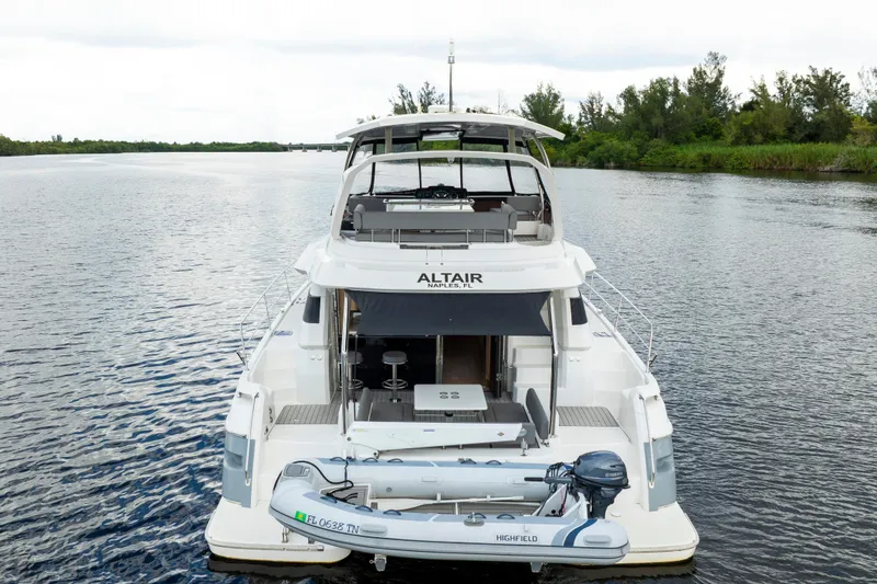 Slide: The Image of 2019 Aquila 44 Yacht on calm water, featuring a small dinghy at the stern. - 55