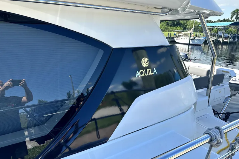 Slide: The Image of 2019 Aquila 44 Yacht docked, showcasing sleek design and logo. - 64