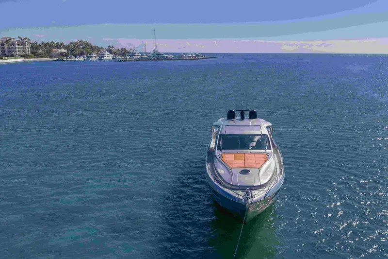 Slide: The Image of 2018 Pershing 70 yacht anchored in serene blue waters near a coastal marina. - 31