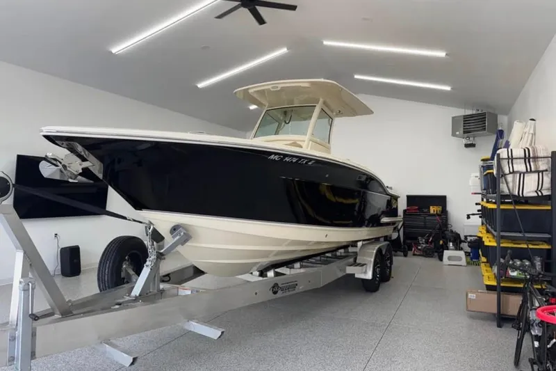 Slide: The Image of 2016 Scout 255 LXF boat on trailer in a well-lit garage. - 10