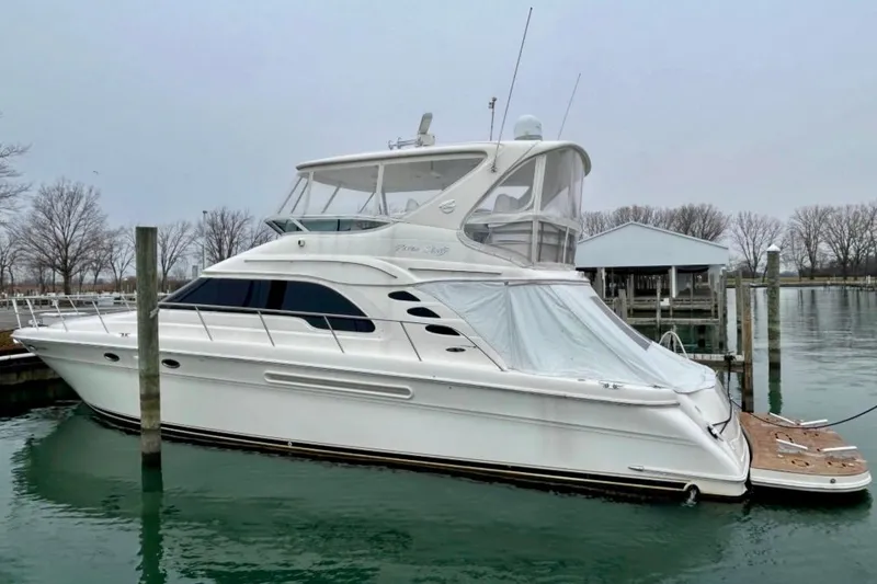 The Image of 2001 Sea Ray 560 Sedan Bridge yacht docked in a marina, overcast sky. - 0
