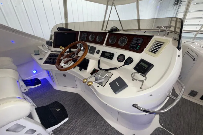 Slide: The Image of 2001 Sea Ray 560 Sedan Bridge helm with wood steering wheel and modern navigation instruments. - 19