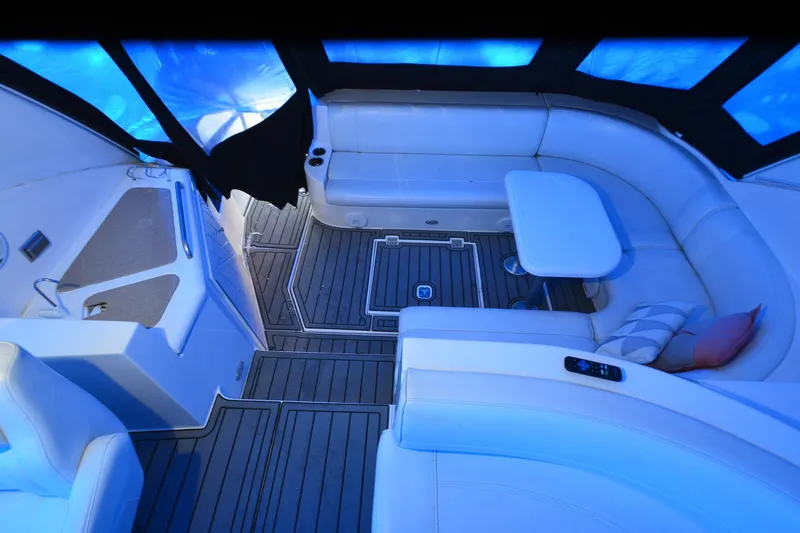 Slide: The Image of 2003 Cruisers Yachts 4370 Express interior with white seating and table, under blue lighting. - 30