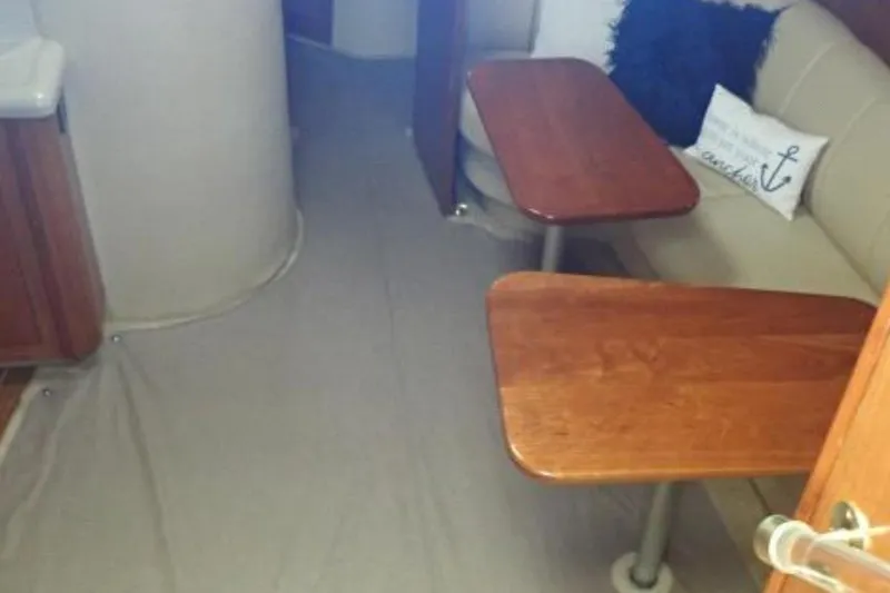 Slide: The Image of Interior of 2003 Cruisers Yachts 4370 Express with wooden tables and beige seating. - 4