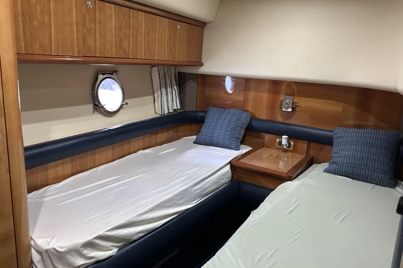 Slide: The Image of 2003 Azimut 55 yacht cabin with twin beds, wooden paneling, and porthole window. - 17