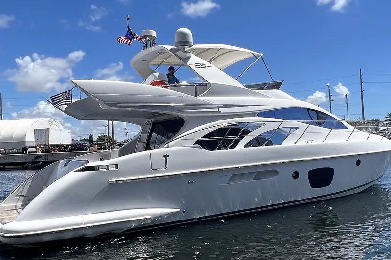 Slide: The Image of 2003 Azimut 55 yacht docked, featuring sleek design and American flags, under a clear blue sky. - 22