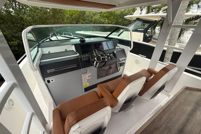 Slide: The Image of 2018 Axopar 37 Sun-Top boat cockpit with modern controls and brown seating. - 10