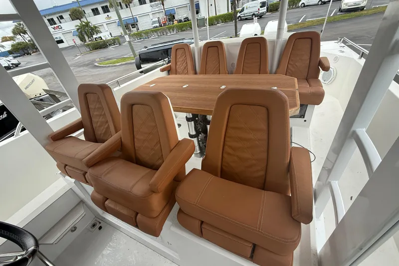 Slide: The Image of 2018 Axopar 37 Sun-Top boat interior with brown leather seating and wooden table. - 12