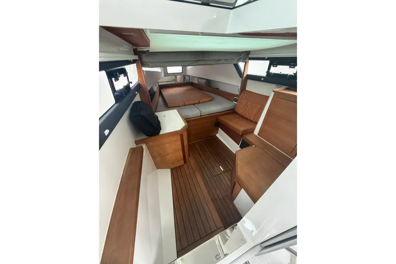 Slide: The Image of 2018 Axopar 37 Sun-Top cabin interior with wood accents and seating area. - 13