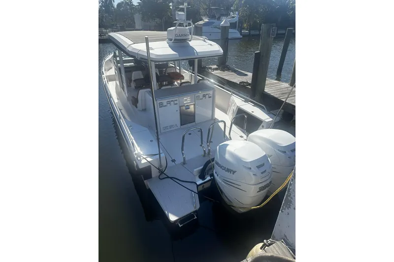 Slide: The Image of 2018 Axopar 37 Sun-Top boat docked, featuring twin Mercury engines. - 2