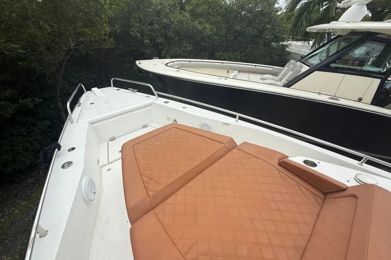 Slide: The Image of 2018 Axopar 37 Sun-Top boat with tan seating, docked near trees. - 7