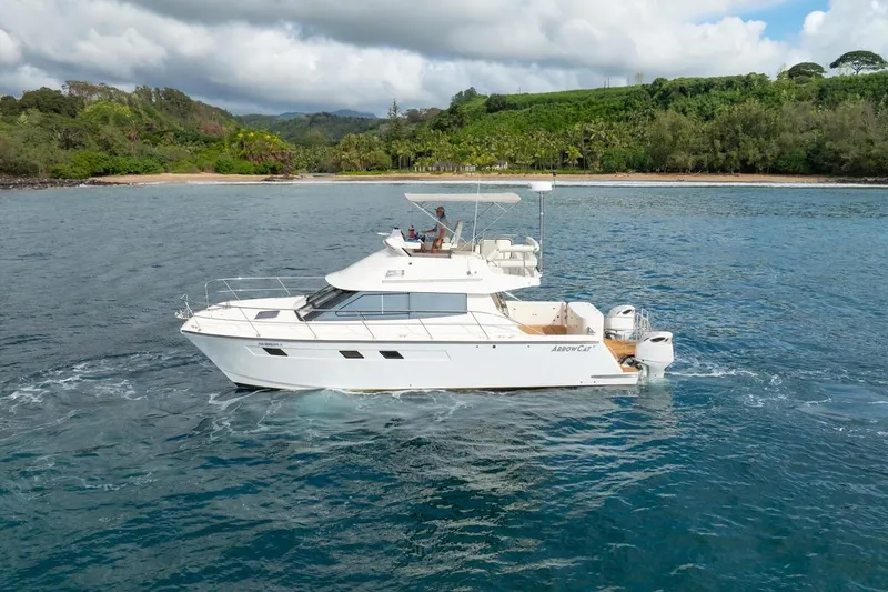 Slide: The Image of 2023 ArrowCat 420 Flybridge yacht cruising near a lush, tropical shoreline. - 10