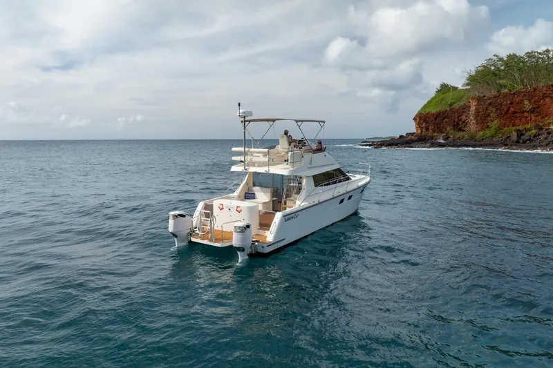 Slide: The Image of 2023 ArrowCat 420 Flybridge yacht cruising near a rocky coastline under a cloudy sky. - 11