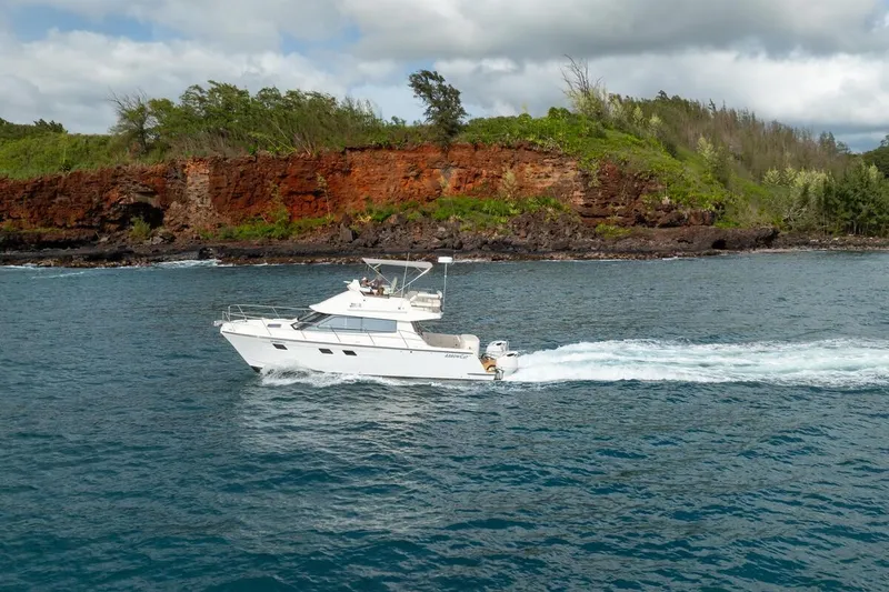 Slide: The Image of 2023 ArrowCat 420 Flybridge cruising near a rocky coastline with lush greenery. - 3