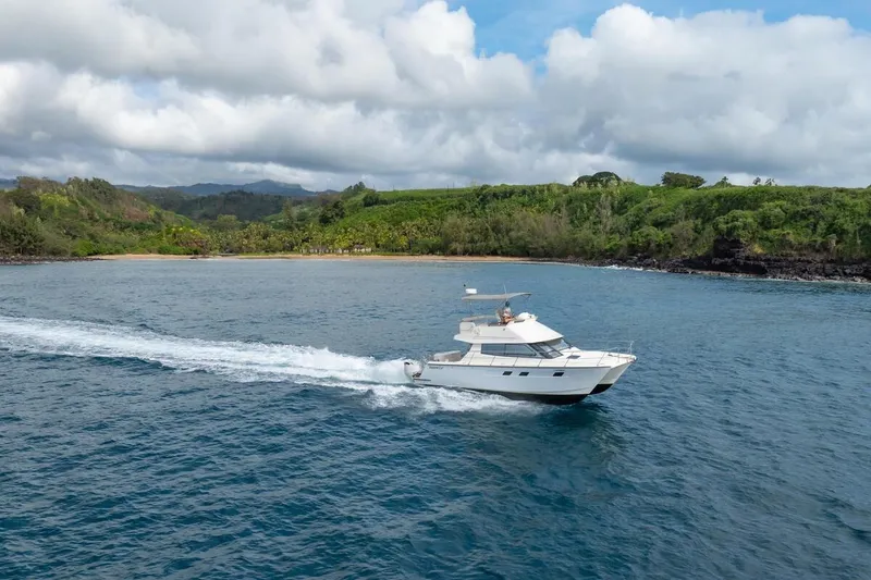 Slide: The Image of 2023 ArrowCat 420 Flybridge cruising near lush green coastline under cloudy sky. - 4
