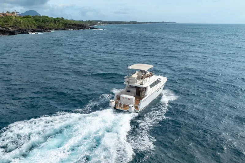 Slide: The Image of 2023 ArrowCat 420 Flybridge cruising on open ocean near lush coastline. - 8