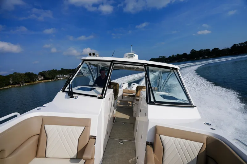 Slide: The Image of 2023 Everglades 340 Dual Console boat interior with lake view, featuring beige seating. - 13