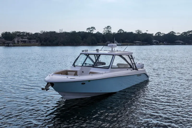 Slide: The Image of 2023 Everglades 340 Dual Console boat on calm water, surrounded by trees and houses. - 37