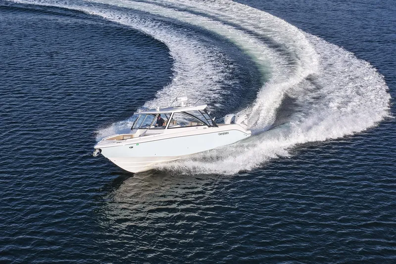 Slide: The Image of 2023 Everglades 340 Dual Console boat making a sharp turn on open water. - 54