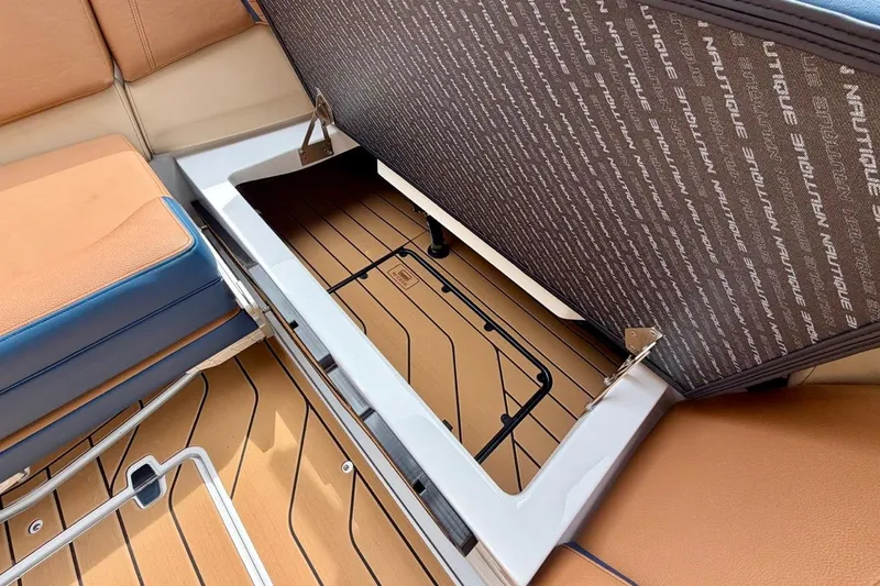 Slide: The Image of 2026 Nautique Super Air Nautique G23 storage compartment with cushioned seating and branded interior. - 32