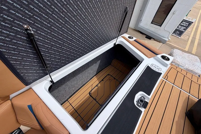 Slide: The Image of 2026 Nautique Super Air Nautique G23 storage compartment with open lid and cup holders. - 35
