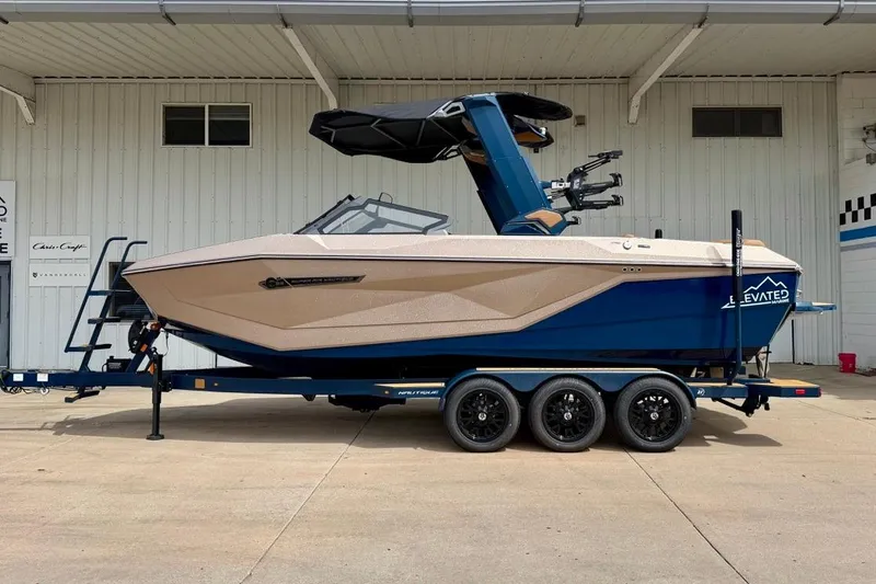 The Image of 2026 Nautique Super Air Nautique G23 boat on trailer, parked outside a building. - 4