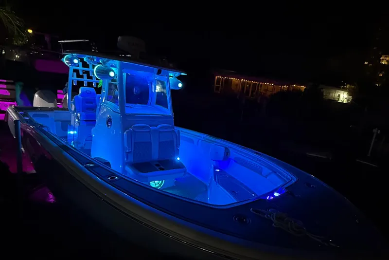 Slide: The Image of 2017 Tidewater 280 CC Adventure boat illuminated with blue LED lights at night. - 10