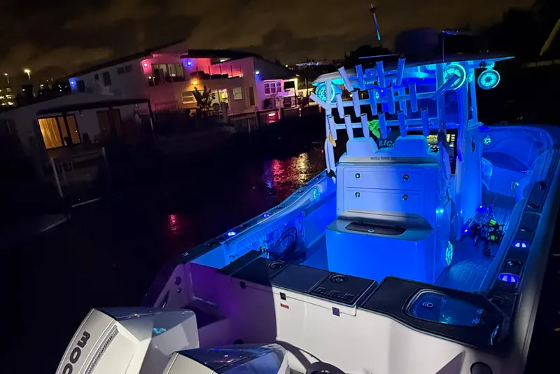 Slide: The Image of 2017 Tidewater 280 CC Adventure boat illuminated with blue lights at night near waterfront homes. - 11