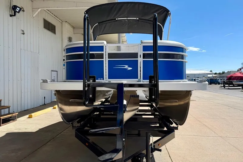 Slide: The Image of 2026 Bennington 22 SX Swingback pontoon boat on trailer, blue exterior, parked outdoors. - 5
