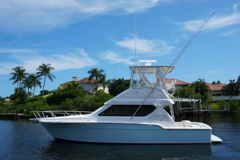 Slide: The Image of 2005 Mirage Yachts 40 Convertible boat on calm water, with palm trees and blue sky background. - 4