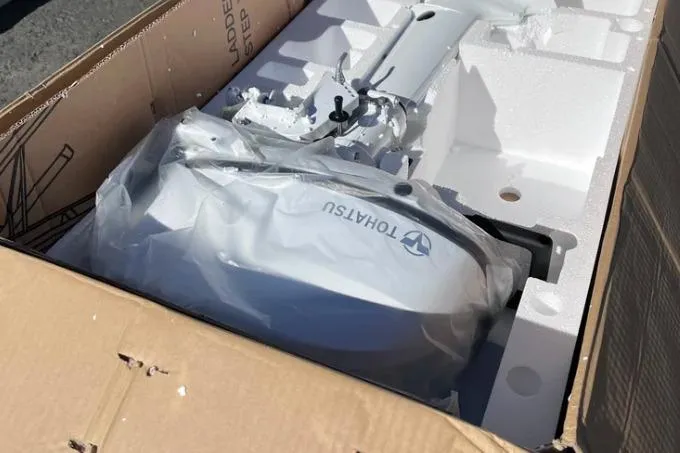 Slide: The Image of Boxed 2022 Corsair 760 model with Tohatsu outboard motor, partially unpacked. - 12