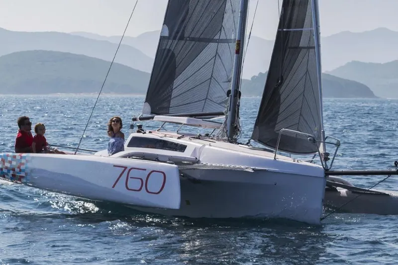 Slide: The Image of 2022 Corsair 760 sailboat on open water with passengers, scenic mountain backdrop. - 4