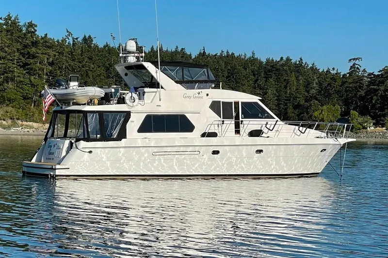 The Image of Compass 55 yacht from 2000 on calm water, surrounded by lush green trees. - 0