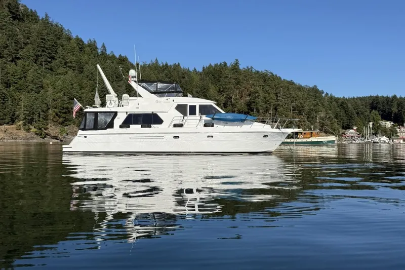Slide: The Image of White 2000 Compass 55 yacht on calm water with forested shoreline background. - 120